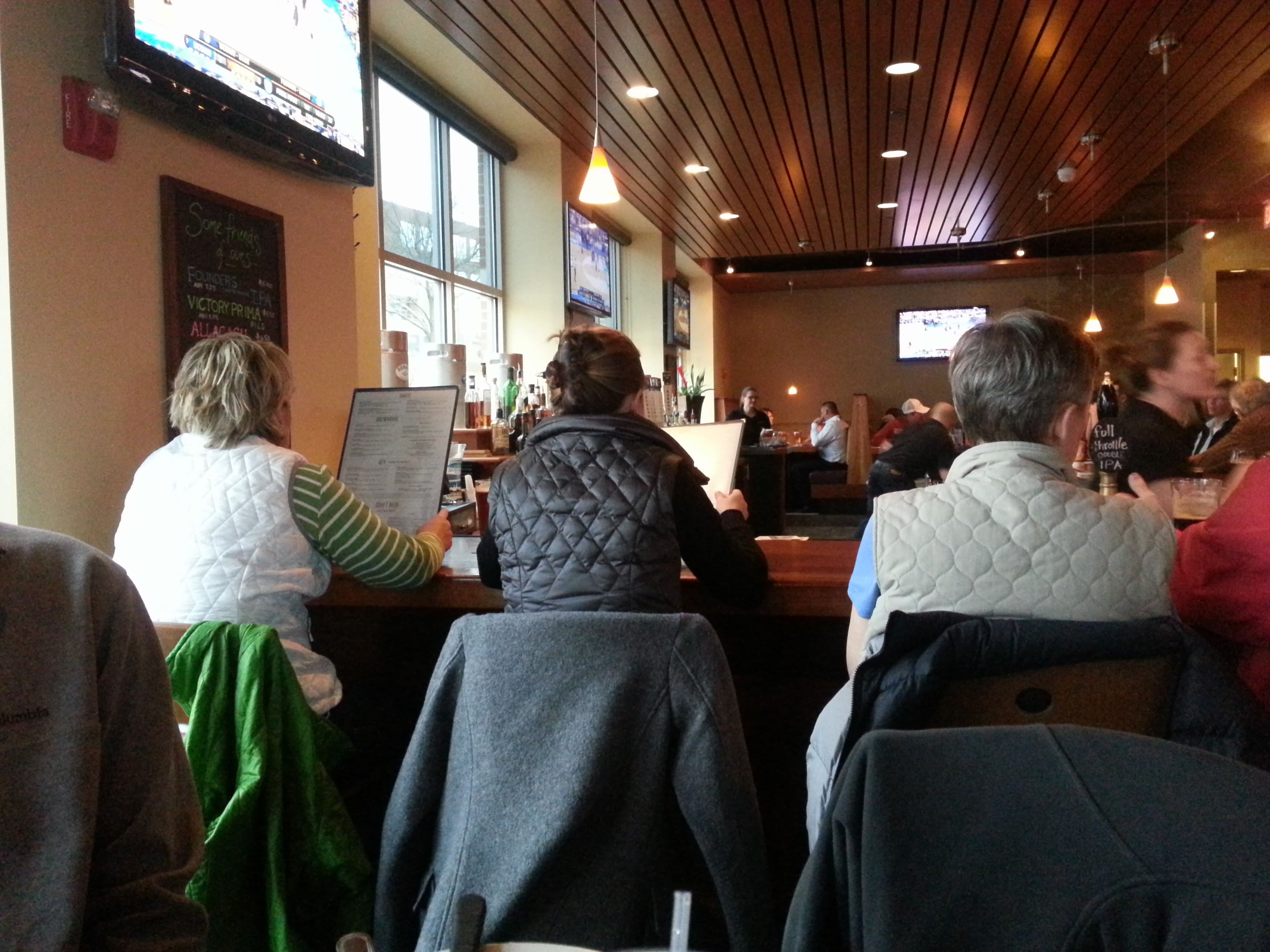 Three women wearing vests while sitting at a bar